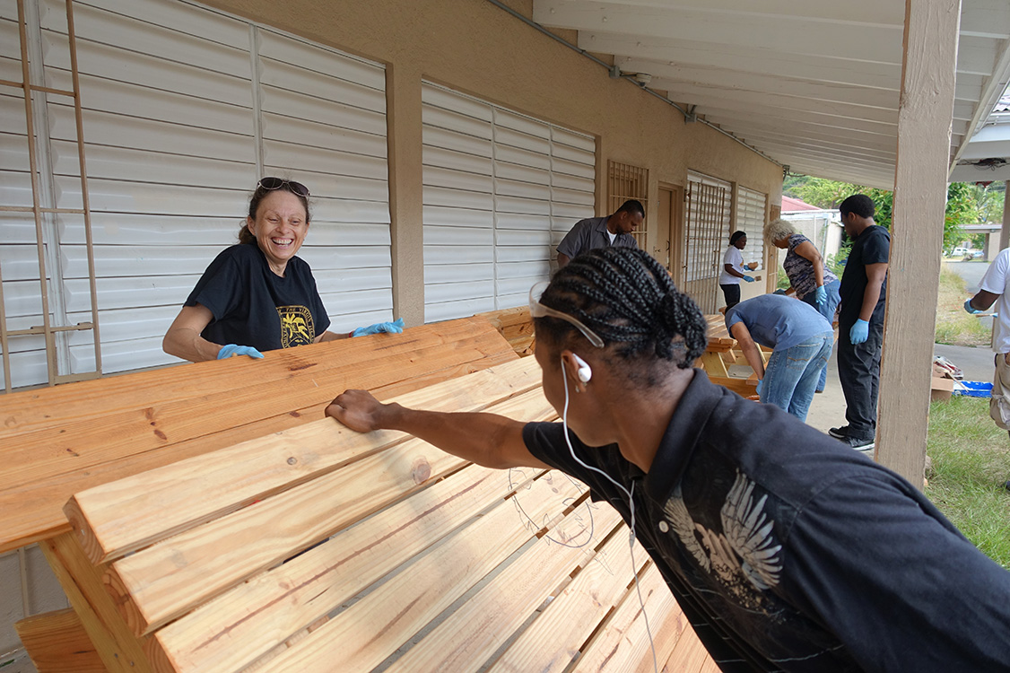 Volunteers paint benches at Addelita Cancryn School. 